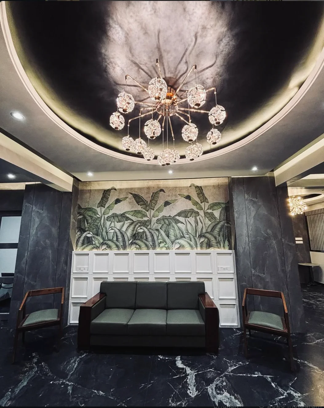 Lobby seating beneath a chandelier and botanical wall mural